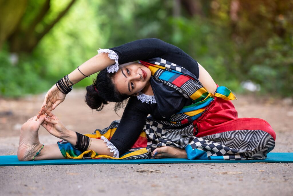 A woman practicing yoga outdoors in colorful attire, showcasing flexibility and mindfulness.