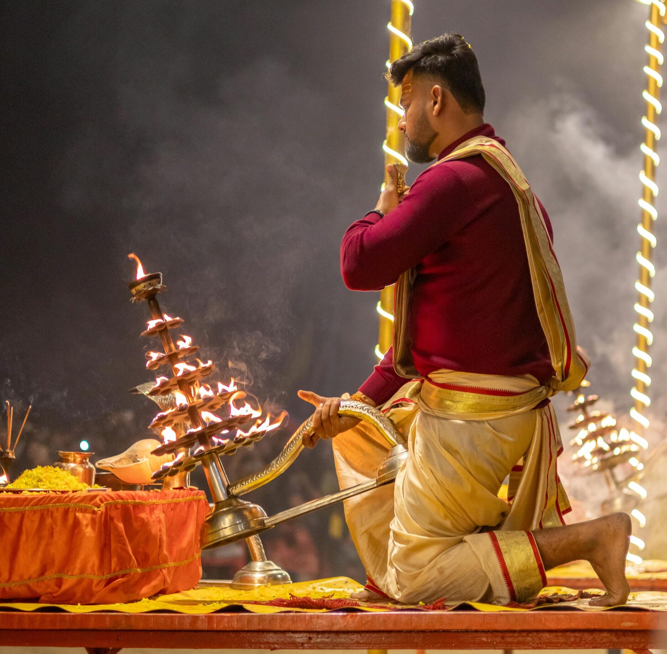 Priest performing Ganga Aarti ceremony on the ghats of Varanasi at night.